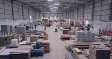 İnsanlar bir mobilya fabrikasında çalışıyor. Mobilya üretimi, mobilya fabrikasının üretim alanının panoram manzarası..