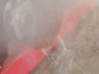 Borudan su akıyor, sıcak su buharlaşıyor. Endüstriyel suyun boşaltılması. Tankın kimyasal temizliğinden sonra atık su.