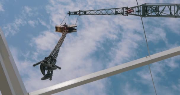 建設クレーンのフックは、カメラの上にハングアップします。タワークレーンの下のビュー。雲と青空を背景に建設クレーン. — ストック動画