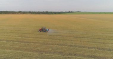Bir traktör buğdaya ot ilacı püskürtür. Traktör buğday tarlalarını ilaçlıyor. İnsansız hava aracının buğday görüntüsüyle tarlayı ilaçlamak