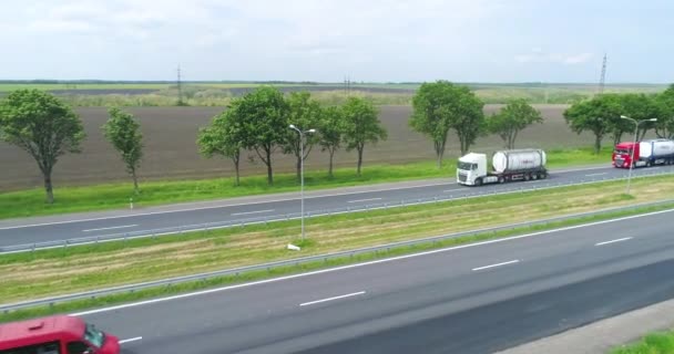 Teherautók lovagol a modern autópályán körül zöld fű tetején kilátás. Teherautó az autópályára néző a drón. — Stock videók