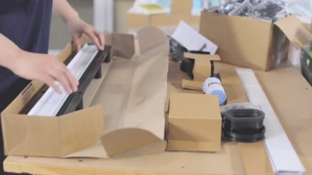 Упаковка готової продукції в коробці. Робітники упаковують готові вироби в коробку — стокове відео