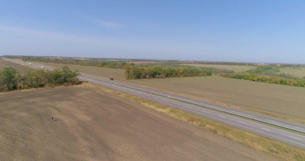 Ciężarówka jedzie wzdłuż drogi w środku pól rolniczych widok z góry. Ciężarówka jedzie po drodze, pola w tle — Wideo stockowe