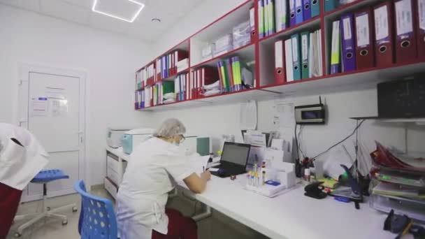 Trabalhadores de laboratório no laboratório. O médico do hospital toma notas. Processo de trabalho em um laboratório médico moderno — Vídeo de Stock