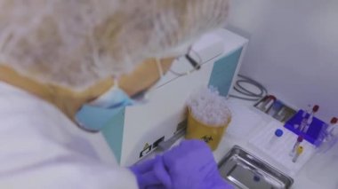 Kadın bir laboratuvar asistanı ellerinde test tüpleri tutuyor. Laboratuvarda iş akışı. Laboratuvarda çalış..