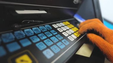Makine operatörü CNC makinesinin tuşlarına basıyor. Yüksek hassasiyetli makine kontrolü