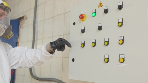Ένας εργάτης με προστατευτική στολή πατάει κουμπιά στον πίνακα ελέγχου. Εργάτης με στολή χημικής προστασίας. Πίνακας ελέγχου εργοστασίων — Αρχείο Βίντεο