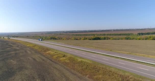 Een vrachtwagen rijdt langs een prachtige weg tussen velden bovenaanzicht. Er rijdt een vrachtwagen langs de snelweg. Uitzicht vanaf een drone. — Stockvideo