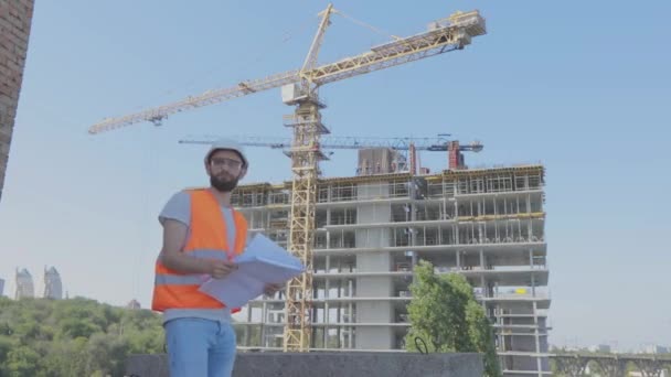 Young engineer at a construction site. An engineer with a drawing at a construction site. Engineer at a construction site — Stock Video