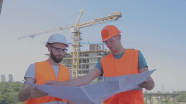 Ingenieros en el fondo de la obra. Constructores en el fondo de la construcción de un edificio de apartamentos — Vídeos de Stock