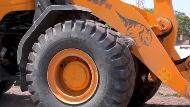 En stor gul grävmaskin kör på en byggarbetsplats. Grävmaskinshjul närbild — Stockvideo