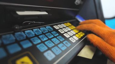 Makine operatörü CNC makinesinin tuşlarına basıyor. Yüksek hassasiyetli makine kontrolü