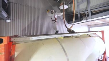 Bir işçi içeriden buharlı bir tank kamyonunun kimyasal temizliğini yapıyor. Tankerin otomatik buhar temizliği. Kimyasal koruma işçisi
