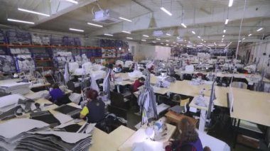 Atölyede zaman turları sırasında bir sürü terzi var. Dikiş endüstrisindeki kadınlar. Büyük bir zaman turu üretimi. Giysi fabrikası iç mimarisi.