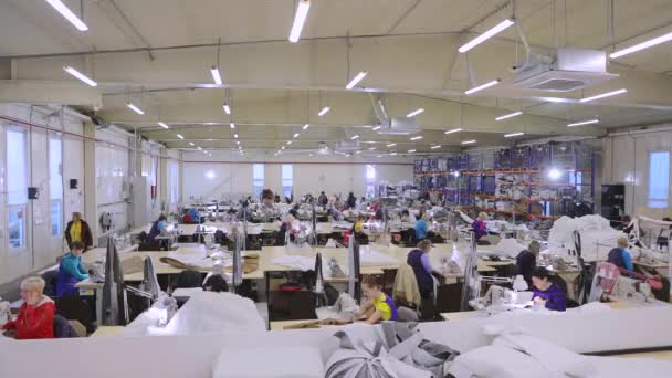 Een grote naaiproductie van tijdrondjes. Versnelde workflow in een kledingfabriek. Er zijn veel naaisters in de werkplaats tijdens de ronden. Kleding fabriek interieur. Vrouwen in de naaiindustrie — Stockvideo