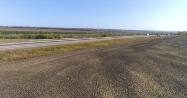 Ciężarówka towarowa jedzie wzdłuż autostrady. Widok z drona. Wóz jedzie po zakrzywionej drodze między polami. — Wideo stockowe