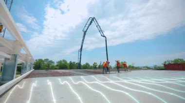 İşçiler, zaman aşımına uğramış beton döşeme yapıyorlar. İşçiler metal yapıya beton döküyorlar. Güçlendirilmiş beton zemin zaman turları oluşturuluyor