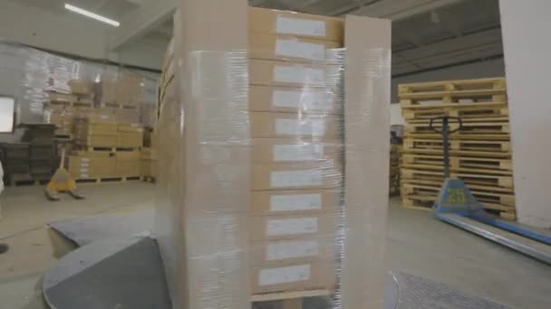 Cajas de embalaje con productos en película de plástico en la fábrica. Una máquina especial envuelve cajas en película de polietileno — Vídeos de Stock