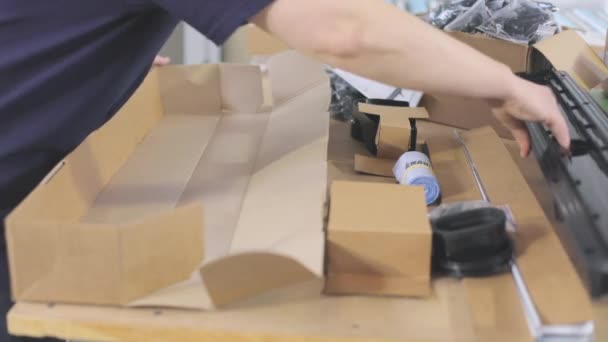 Працівник поміщає товар у коробку для відправки клієнту. Упаковка пластикових деталей у коробці . — стокове відео