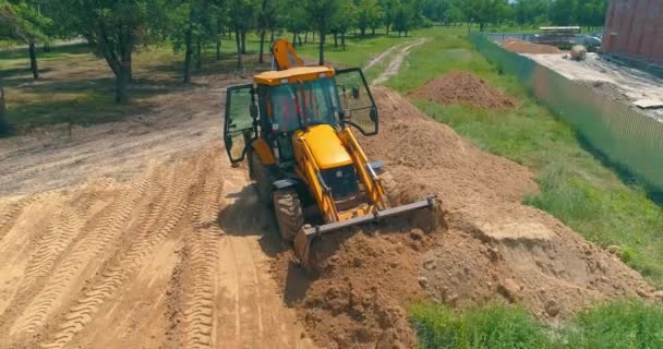 İnşaat alanında büyük sarı bir traktör. İnşaat alanında çalışma süreci. İnşaat alanında profesyonel ekipman. — Stok video