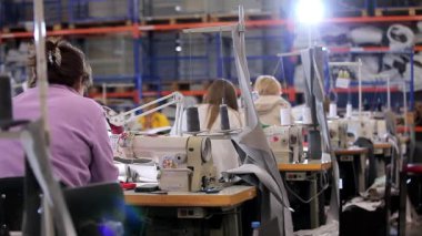 Birçok terzi bir giyim fabrikasında çalışır. Bir giyim fabrikasında çalışma süreci. Büyük dikiş atölyesi. Terziler fabrikada ürün yapar. Kumaş fabrikası