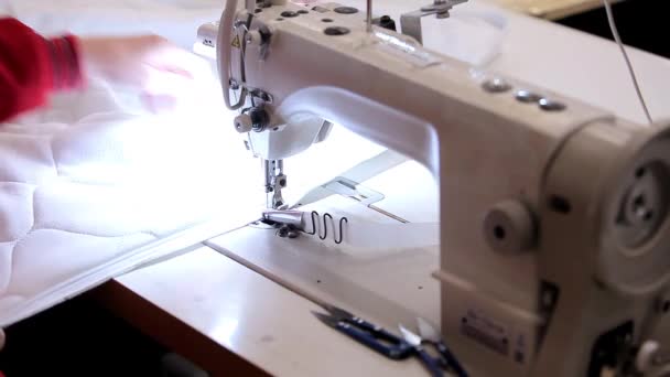 Une couturière fait un gros plan sur la machine à coudre. Gros plan d'un processus de couture dans une usine de couture. Processus de couture sur équipement professionnel. — Video