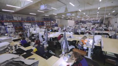 Büyük dikiş atölyesi. Birçok terzi bir giyim fabrikasında çalışır. Bir giyim fabrikasında çalışma süreci. Terziler fabrikada ürün üretir. Kumaş fabrikası