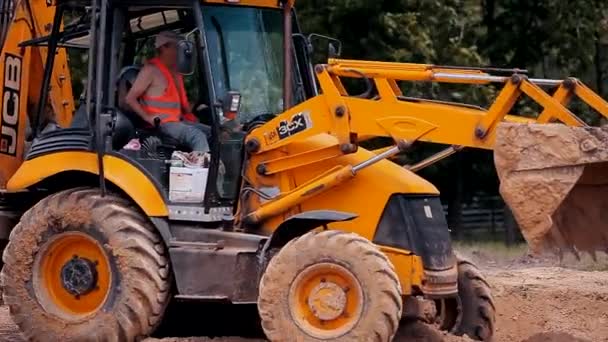 Gelber Traktor auf einer Baustelle. Professionelle Baumaschinen. Arbeitsprozess auf der Baustelle — Stockvideo