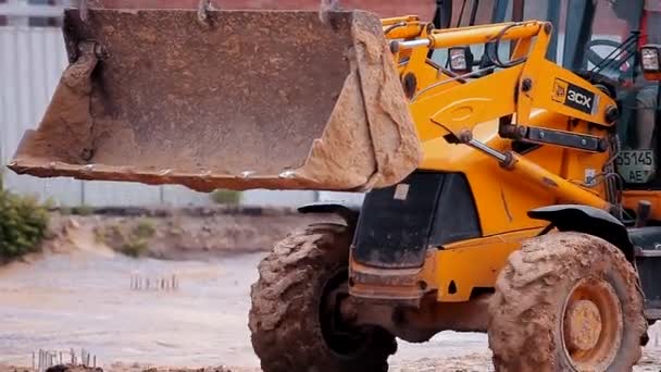 Tracteur jaune sur un chantier. Processus de travail sur un chantier. Matériel de construction professionnel. — Video