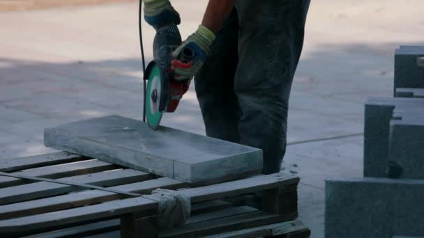 Un trabajador corta una losa de granito con una amoladora. Proceso de trabajo en una obra. Trabajar como amoladora en una obra de construcción — Vídeo de stock