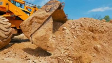 İnşaat alanında çalışma süreci. Traktör kovası yaklaş. Bir traktör inşaat alanında çukur kazıyor..