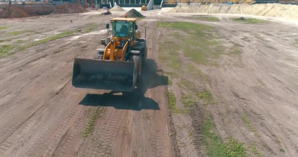 İnşaat alanında büyük sarı bir traktör. İnşaat alanında çalışma süreci. İnşaat alanında profesyonel ekipman. — Stok video