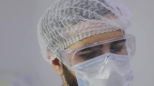 Κοντινό πλάνο του προσώπου μιας νοσοκόμας εργαστηρίου που φοράει μάσκα και γυαλιά. Πλάνο προσώπου εργαζομένου εργαστηρίου — Αρχείο Βίντεο