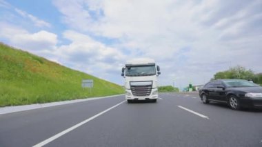 Tankerli bir kamyon güneşli havada otoyola çıkıyor. Bir kamyon konvoyu otoyol boyunca sürer. Otoyol boyunca giden beyaz bir kamyon..
