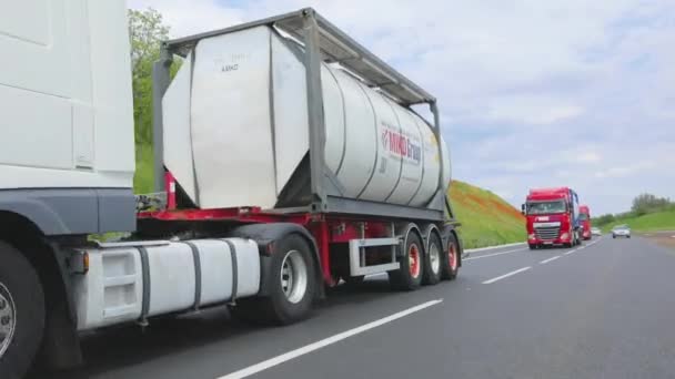 Ciężarówki jadą wzdłuż drogi. Ciężarówka z cysterną jedzie wzdłuż autostrady z bliska. Transport towarów niebezpiecznych — Wideo stockowe