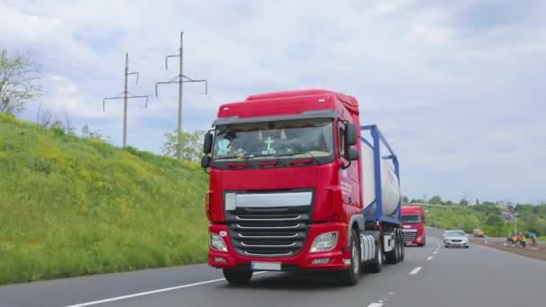 The red truck is driving along the highway. A group of trucks are driving along the highway. Modern trucks transport liquid cargo in tanks — Stock Video