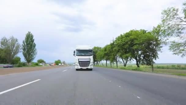 White truck driving along the highway. A truck with a tanker drives on the highway in sunny weather. A convoy of trucks drives along the highway — Stock Video