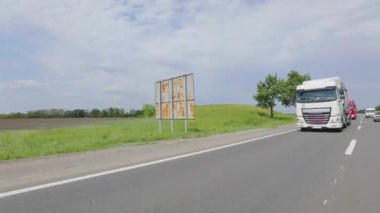 Tankerli bir kamyon güneşli havada otoyola çıkıyor. Bir kamyon konvoyu otoyol boyunca sürer. Otoyol boyunca giden beyaz bir kamyon..