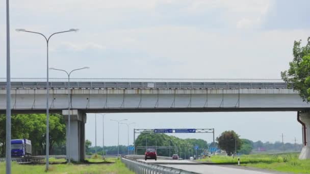 Transport interchange. Trucks are driving across the bridge over the highway. Evto ride under the bridge — 图库视频影像