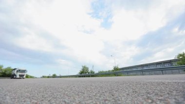 Kamera yolu daha düşük bir açıdan çeker. Bir otoyolu alçak bir açıdan vurmak. Otoyol boyunca kameranın önünden arabalar geçiyor..