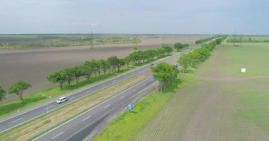 Otoyolda arabalar ve kamyonlarla uçmak. Modern bir otoyolun üzerinde uçuyor. İHA 'dan ufuk çizgisine uzanan yol