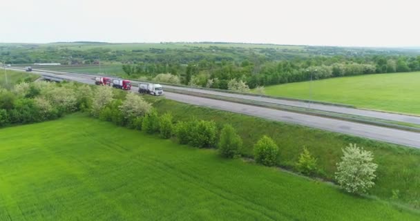 Tres camiones están conduciendo a lo largo de la carretera, vista aérea. Volando sobre la autopista a lo largo de la cual viajan los camiones de combustible. — Vídeo de stock