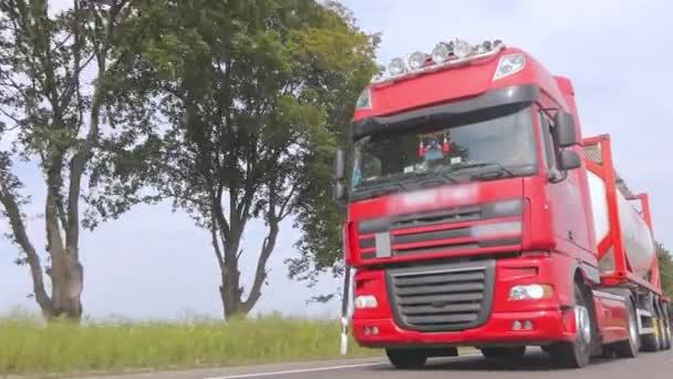 O camião vermelho está a conduzir pela auto-estrada. Um grupo de caminhões está dirigindo ao longo da estrada. Caminhões modernos transportam carga líquida em tanques — Vídeo de Stock