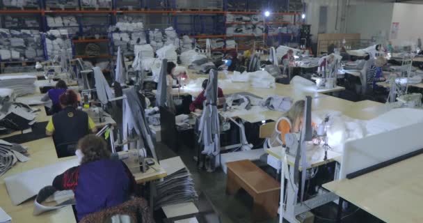 Большая швейная мастерская. Рабочий процесс на швейной фабрике. Многие швеи работают на швейной фабрике. Швы производят продукцию на заводе. Швейная фабрика — стоковое видео