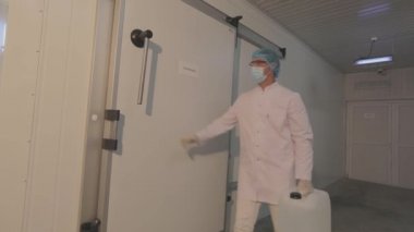 Sümük şişesi olan bir işçi. Modern bir üretim tesisinde çalışan bir işçi. Beyaz, temiz üretim alanı.