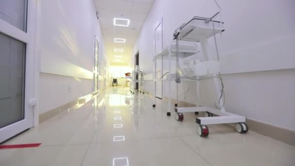 De lege, heldere gang van de kliniek. Interieur van een moderne kliniek. Corridors van een modern ziekenhuis. De camera loopt langs de lege gang van het ziekenhuis. — Stockvideo