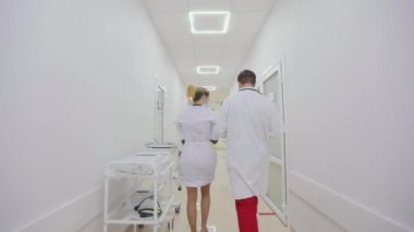 Koruyucu giysili doktorlar hastane koridorlarında yürürler. Antiviral korumadaki doktorlar parlak hastane koridorlarında yürüyorlar.