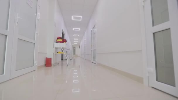 Камера стоїть уздовж порожнього коридору лікарні. Коридори сучасної лікарні. Порожній, світлий коридор клініки. Інтер'єр сучасної клініки — стокове відео