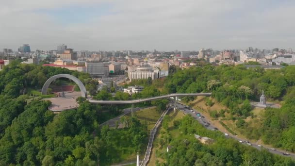 Halkın dostluk kemerinden yaya köprüsü. Kiev 'de yeni binalar. Kiev 'in turist bölgesinin üzerinden uçacağız. Kiev şehrindeki yaya köprüsü. Kiev 'deki yaya köprüsünün üzerinden uçuyor. — Stok video