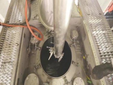 Bir işçi içeriden buharlı bir tank kamyonunun kimyasal temizliğini yapıyor. Tankerin otomatik buhar temizliği. Kimyasal koruma işçisi